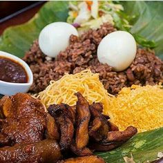 a plate with meat, rice and other food items on it next to a bowl of sauce