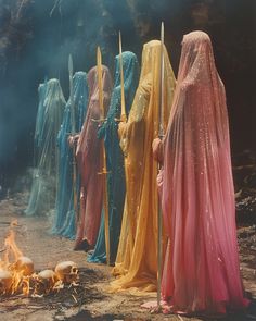 a group of women dressed in colorful clothing standing next to a campfire with torches