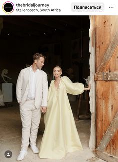 a man and woman standing next to each other in front of a wooden barn door