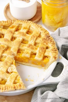 a pie on a plate next to a jar of orange juice and a glass of orange juice