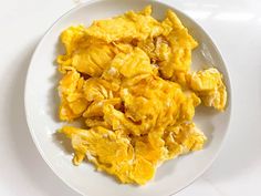 a white plate topped with scrambled eggs on top of a table