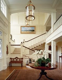 an elegant entry way with white flowers on the table and stairs leading up to the second floor