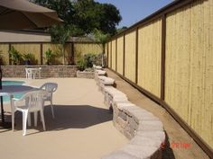 a patio with tables and chairs next to a fence