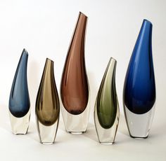 five different colored vases are lined up against a white background, one is upside down