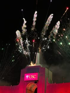 fireworks are lit up in the night sky above a building with a usc sign