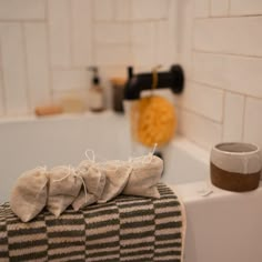 three rolls of toilet paper sitting on top of a bath tub next to a cup