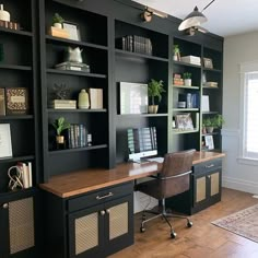 a home office with black bookcases and wooden desk