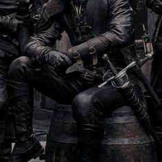 a group of men dressed in black sitting next to each other on top of barrels