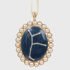 a blue and white pendant with pearls around it