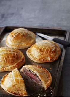 several pastries on a baking sheet with a knife and fork next to them,