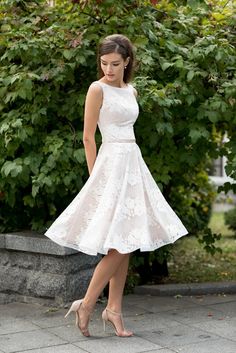 a woman in a white dress is posing for the camera with her hands on her hips