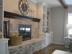 a living room filled with furniture and a clock on top of the fireplace mantel