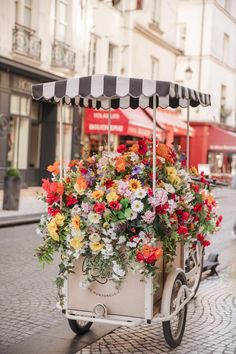 a flower cart with flowers in it on the street