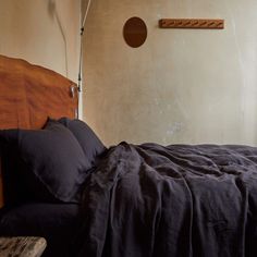 a bed with black linens and pillows in a small room next to a window