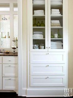 a bathroom with white cabinets and towels in it