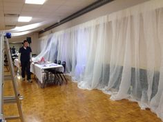 a man standing next to a white table covered in curtains