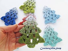 crocheted christmas tree ornaments are being held by a person's hand in front of them