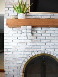 a television mounted on top of a brick wall next to a fire place with a potted plant