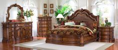 a bed room with a neatly made bed and wooden furniture on the hardwood flooring