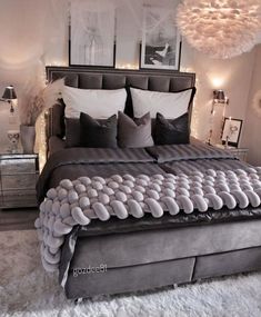 a large bed with lots of pillows and lights on the headboard, in a bedroom