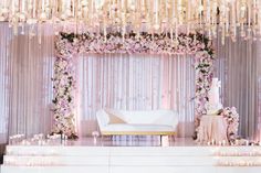 a white couch sitting under a chandelier covered in flowers