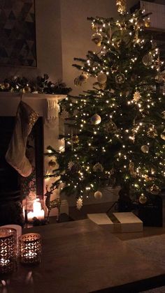 a lit christmas tree in front of a fireplace