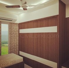 a room with a bed, ceiling fan and window overlooking the valley outside it is empty