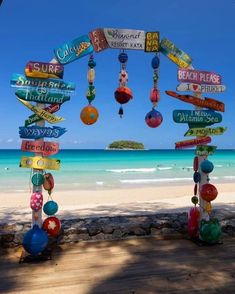 a sign post on the beach with many different signs hanging from it's sides