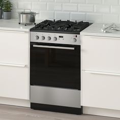 a stove top oven sitting inside of a kitchen next to a white countertop with pots and pans on it