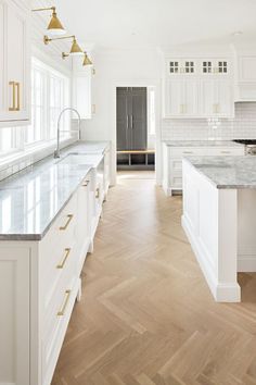 a large kitchen with white cabinets and marble counter tops