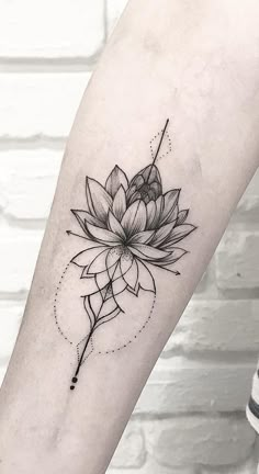 a black and white lotus flower tattoo on the right forearm, with an arrow in the middle