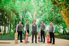 four young men holding skateboards in front of trees