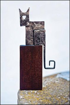 two metal objects sitting on top of a wooden block in the shape of a cat