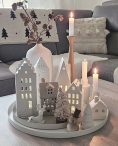 candles are lit on a tray in front of a living room couch and coffee table