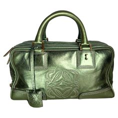 Loewe Amazona 29 Zip Around in Metallic Green Lambskin Leather Top handle bag in boxy trunk style is back in fashion in 2024 thanks to shows by Prada and Miumiu. The Loewe Amazona bag is a stylish and functional option for everyday use, with a structured yet soft shape. Originally designer in 1975 and inspired by female warriors of Greek Mythology, this bag has been updated to include a padlock, metal feet, interior pockets. Its lightweight design makes it a practical choice for any occasion. CO Sac Loewe, Designer Green Bags With Leather Handles, Luxury Green Shoulder Bag With Leather Lining, Luxury Green Bags With Metal Hardware, Loewe Puzzle Bag Green, Luxury Green Shoulder Bag With Metal Hardware, Loewe Amazona, Puzzle Bag, Female Warriors