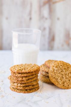 a stack of oatmeal cookies next to a glass of milk on a table