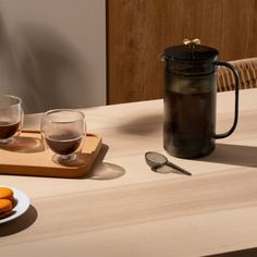 a table topped with two plates of food next to a coffee pot and glass cups