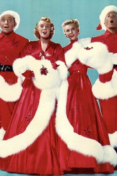 three women in red dresses and white furs are posing for a christmas photo with santa claus