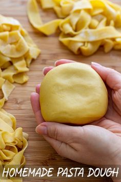 a person holding a doughnut in front of some uncooked pasta on a cutting board