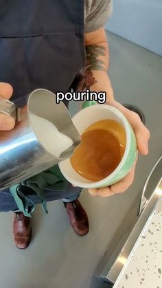 a person pouring coffee into a cup on top of a metal counter with the words purring above it