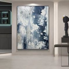 an abstract painting is displayed in a white room with black and grey accents, along with a modern chair