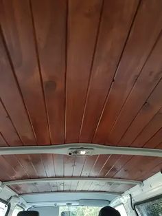 the interior of a van with wood paneling on the ceiling and two people sitting in the back seat