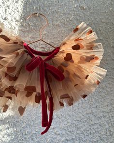 a red and white dress hanging from a hook on a wall with hearts painted on it