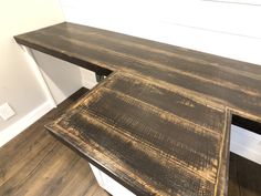 a wooden bench sitting on top of a hard wood floor next to a white wall