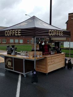 an outdoor coffee stand on the side of a road with people sitting at tables under it