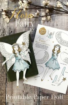 the paper doll fairy is next to its box