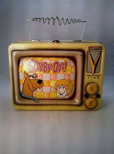 an old yellow television with cartoon characters on the front and sides, sitting on a white surface