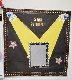 a black and yellow star student bulletin board with lights on it's sides, in front of a refrigerator