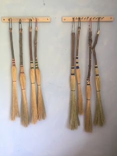 four brooms are hanging on the wall and one is made out of wooden sticks