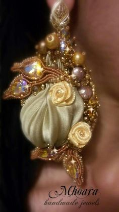 a close up of a person's ear with gold and white jewelry on it